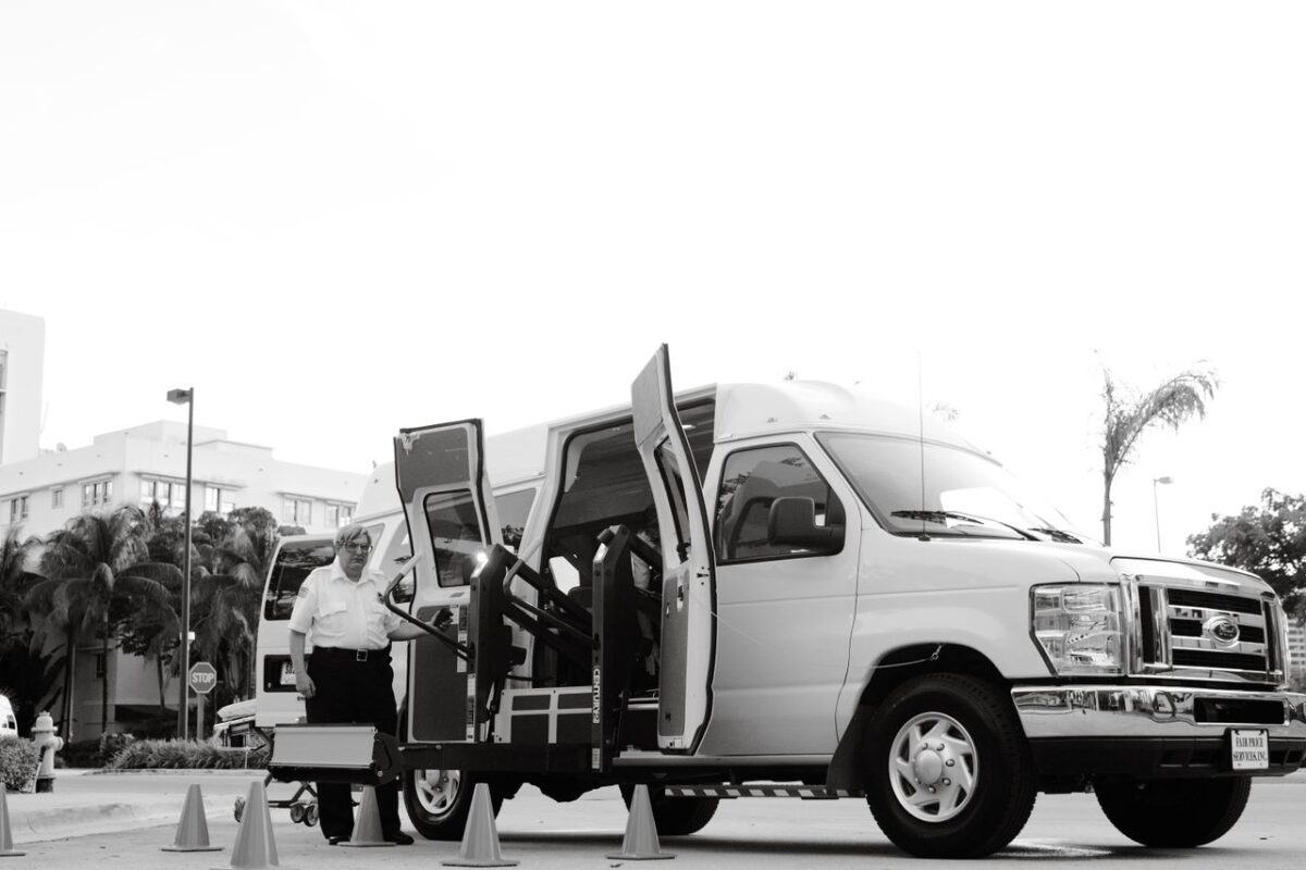 À propos A black and white image depicting an accessible transport van with a lift, enhancing mobility for passengers with disabilities.